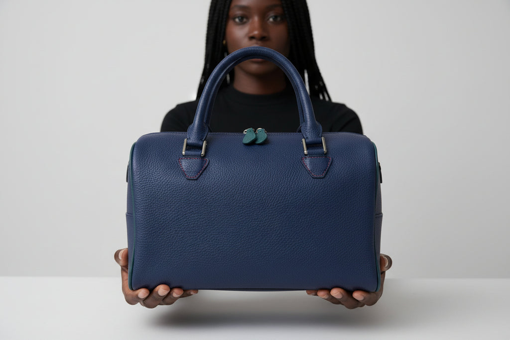 The Cassie handmade leather handbag in blueberry. Being held- front view